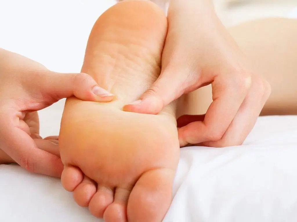 Dita premono sulla pianta del piede durante trattamento di riflessologia plantare