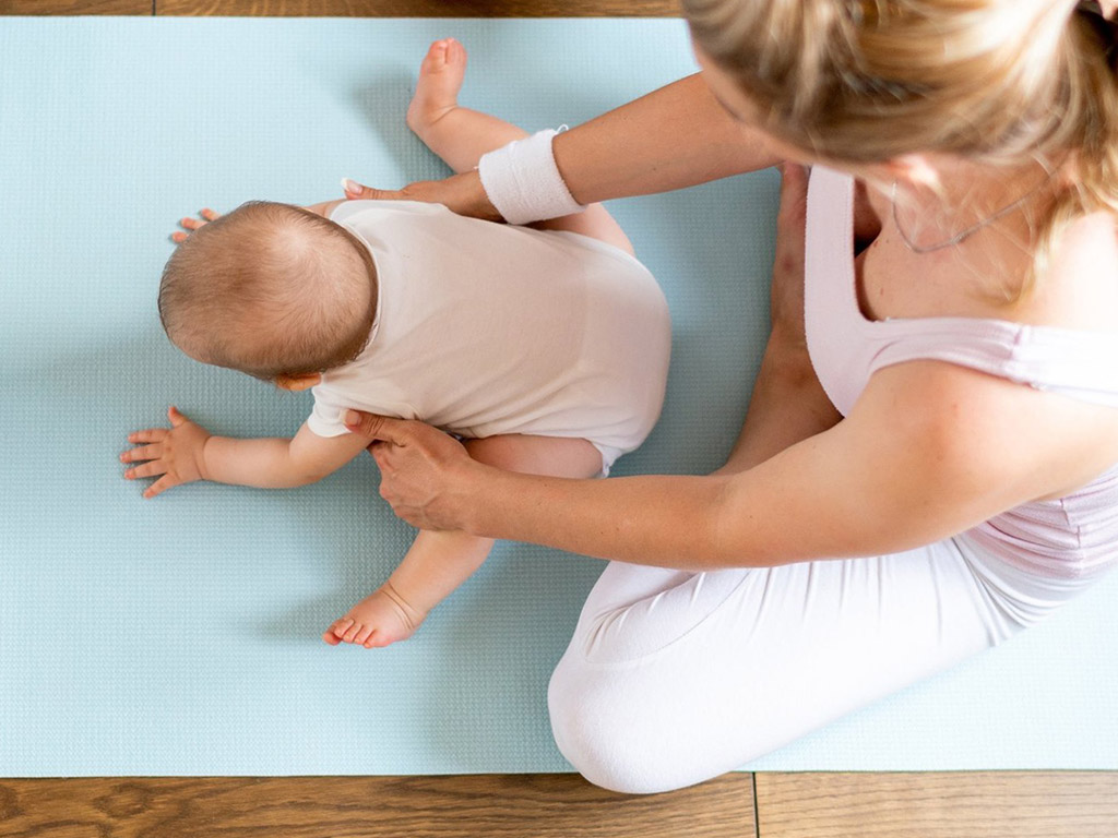 Momento durante lezione di yoga con la mamma e il suo bambino